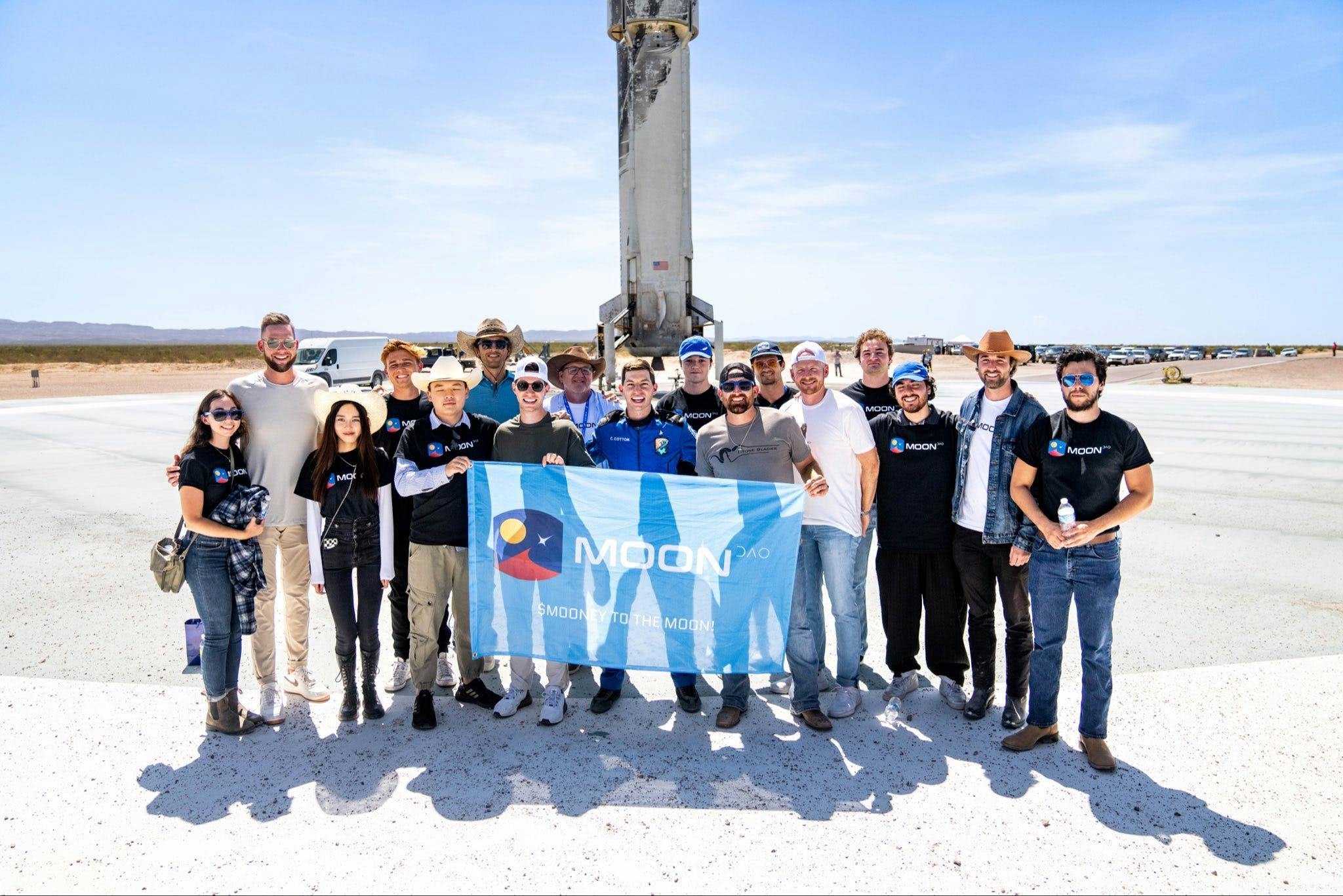 MoonDAO celebrating the launch of their first astronaut (Coby Cotton) in front of Blue Origin's rocket